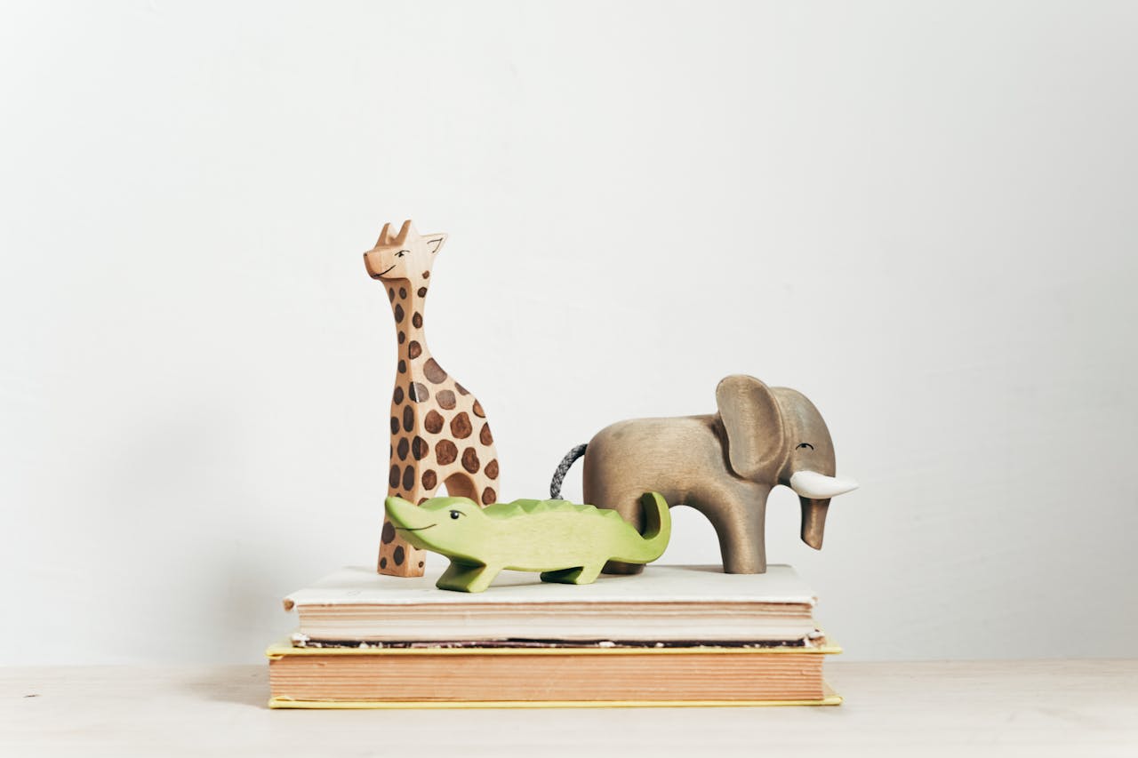 Charming display of wooden animal toys on stacked books, perfect for children's decor.